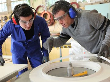 Männer mit Schallschutz beugen sich über ein Gerät